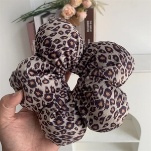Detail of a large leopard print scrunchie made of soft velvet fabric with ruffles