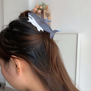 Detail view of the gray and white shark-shaped hair claw clip holding hair in a ponytail