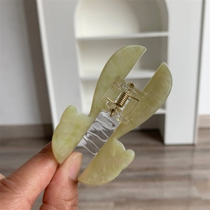 Dettaglio ravvicinato della molletta per capelli in acetato verde con molla in metallo