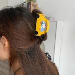 Detailed view of a yellow cartoon car acetate hair claw clip worn in hair