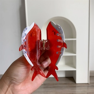 Dettaglio della molletta per capelli in acetato rosso a forma di balena lucida