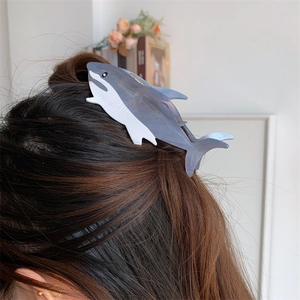 Detail of shark-shaped hair claw clip in translucent grey and white on dark brown hair
