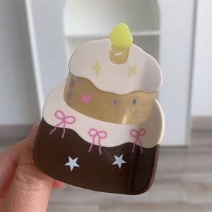 Detail of multi-layered acetic acid cake hair claw with pink bow and candle design