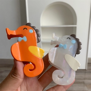 Schattige haarklemmen van acetaat in zeepaardvorm in de kleuren oranje en parelwit