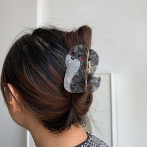 Dettaglio del fermaglio per capelli in acetato a forma di foca grigio marmo indossato sui capelli