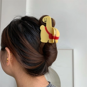 Détail de la pince à cheveux girafe jaune avec sac à dos sur une coiffure en queue de cheval