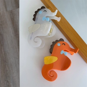 Detail van schattige zeepaardje haarklemmen van acetaat in oranje en wit met design