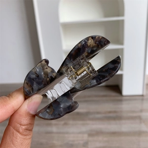 Dettaglio della grande pinza per capelli in acetato grigio marmorizzato con molla
