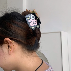 Close-up of a bear paw shaped black hair claw with pink floral patterns on a bun