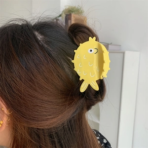 Cute yellow pufferfish hair claw clip shown on long dark hair for styling view