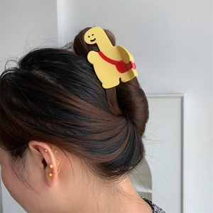 Pince à cheveux girafe jaune avec détail sac à dos rouge portée sur un chignon élégant