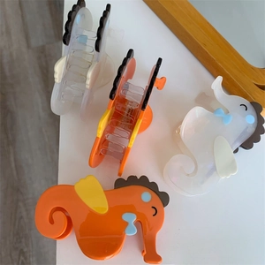 Detail van zeepaardje haarklemmen in oranje en parelwit met schattige strikjes