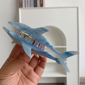 Close-up of a blue and white marble acetate shark hair claw clip with metal spring detail
