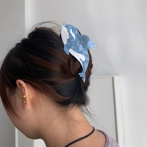 Detailed view of large orca-shaped acetate hair claw clip with blue marble finish on hair