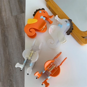 Gedetailleerde weergave van zeepaardje haarklemmen in oranje en wit acetaat
