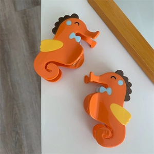 Detail van schattige oranje zeepaardje haarklemmen met glanzende afwerking op tafel