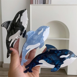 Detail view of acetate whale hair claws featuring marble textures and metal spring mechanisms