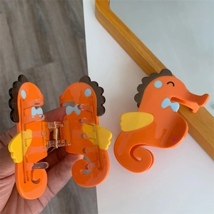 Detail van de oranje acetaat haarklem in zeepaardvorm met kleurrijke vinnaccenten