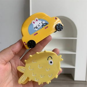 Detail of yellow car and pufferfish hair clips with cute rabbit graphics in acetate