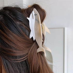 Large shark-shaped hair claw clip in white acetate shown styling long brunette hair
