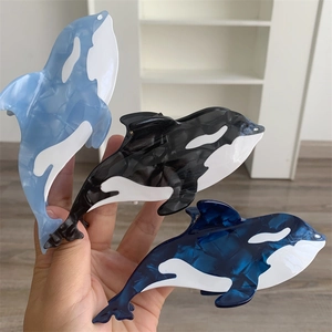 Detailed view of orca-shaped acetate hair claws in dark blue, light blue, and black colors