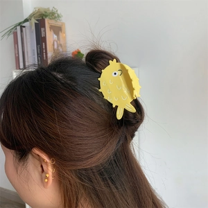 Detailed view of a bright yellow pufferfish acetate hair claw clip worn on a half-up bun