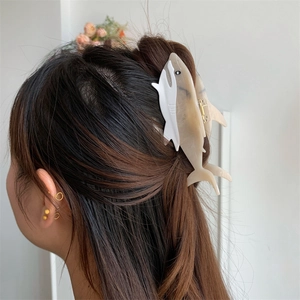 Detailed macro view of shark-shaped acetate hair claw with marble texture on hair bun