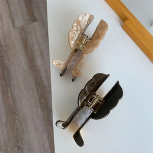 Detailed view of wavy acetate hair claws in marble cream and dark coffee brown