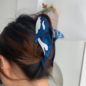 Detailed view of an orca shaped acetate hair claw clip worn on long braided hair