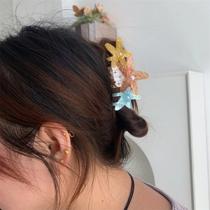 Detailed view of starfish hair claw with crystals and pearls worn on dark brown hair
