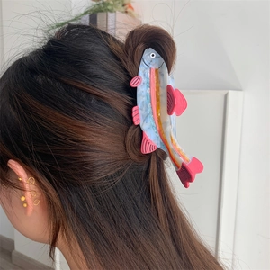 Detail of fish-shaped acetate hair claw clip with colorful marble pattern on hair