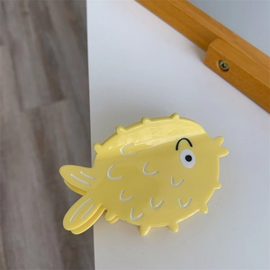 Detailed view of a cute yellow pufferfish hair claw clip made of acetic acid material