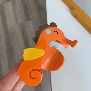 Gedetailleerde close-up van een oranje zeepaardje haarklem met een glanzende afwerking