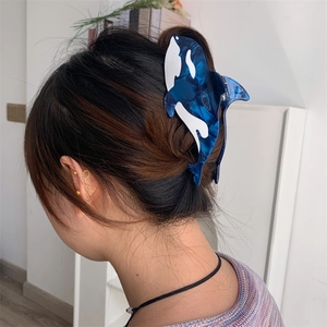 Detailed view of large orca-shaped acetate hair claw clip worn in hair by a woman