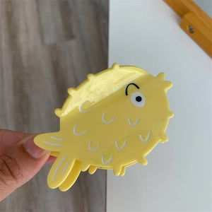 Macro detail of yellow pufferfish acetate hair claw clip showing glossy scales and cute design