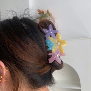 Detailed view of colorful starfish hair claws with pearls and rhinestones on a woman's hair