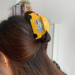 Detail view of a yellow car-shaped hair claw clip with rabbit illustration on model