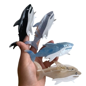 Shark-shaped acetate hair claw clips in four colors shown being held in hand
