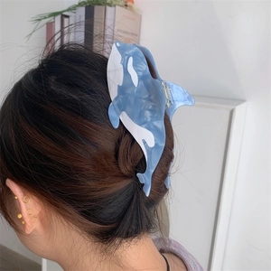Detailed view of large orca-shaped blue acetate hair claw clip worn on a woman's hair