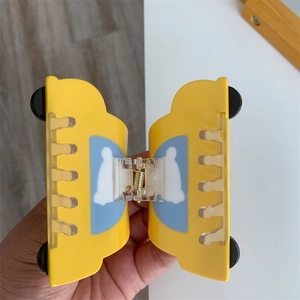 Detail view of a cute yellow cartoon car hair claw clip with light blue windows