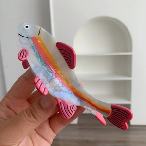 Detail view of pink acetate fish hair claw clip with delicate marble texture and patterns