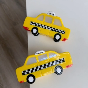 Detailed close-up of a yellow taxi-shaped acetate hair claw with black and white checkers
