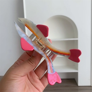 Detail of fish-shaped hair claw clip with pink accents and gold metal spring mechanism