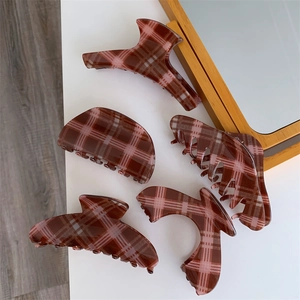 Detail view of five different geometric red plaid hair claws and shark clips on a table