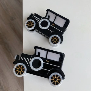 Close-up of retro black car-shaped acetate hair claw clips with white marble wheels