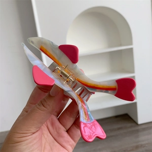 Detailed close-up of pink acetate fish hair claw clip with colorful rainbow stripes