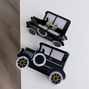 Detail view of vintage car-shaped hair clips in black acetate with marble wheel patterns