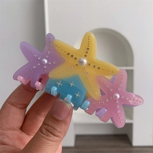 Detailed close-up of a colorful starfish hair claw featuring crystals and white faux pearls