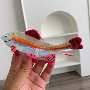 Detail view of pink acetate fish hair claw clip with colorful stripes and pearly texture