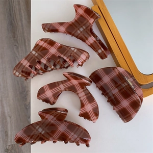 Five pieces of brown and pink plaid hair claws in various shapes on a white surface